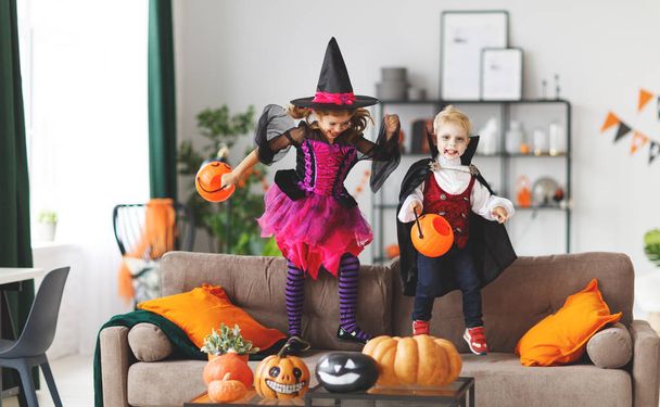 niños felices con disfraces de bruja y vampiro preparando el hogar para las vacaciones Hallowee
 - Foto, imagen