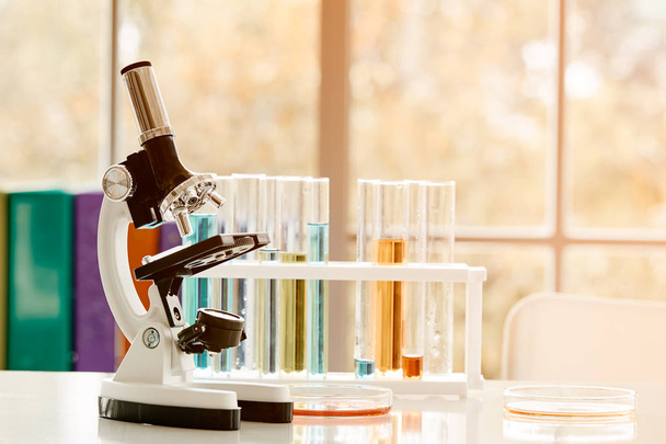 Mikroskop auf dem Tisch mit Laborausstattung im Chemielabor mit Lichtstrahl; Forschungs- und Entwicklungskonzept des Wissenschaftslabors - Foto, Bild