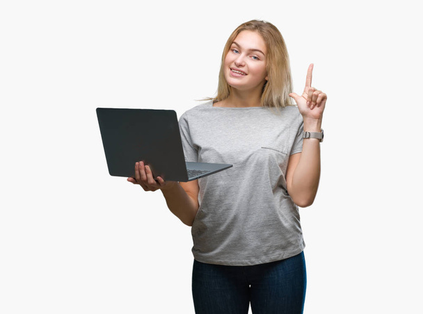 Fiatal kaukázusi nő elszigetelt háttér meglepett mutatóujjal egy ötletet vagy kérdést boldog arc, az első laptop számítógép segítségével - Fotó, kép