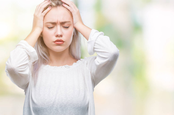 Jonge blonde vrouw over geïsoleerde achtergrond die lijdt aan hoofdpijn wanhopig en gestrest omdat pijn en migraine. Handen op het hoofd. - Foto, afbeelding