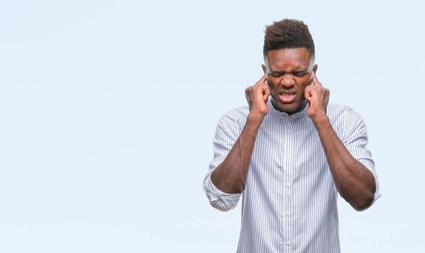 Giovane uomo afroamericano su sfondo isolato che copre le orecchie con le dita con espressione infastidita per il rumore della musica ad alto volume. Concetto di sordo
. - Foto, immagini
