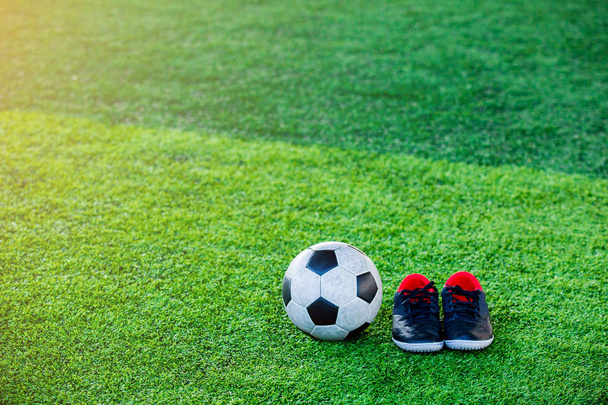 Fútbol y negro zapatos deportivos rojos en césped artificial verde para el entrenamiento de jugadores de fútbol y jugar fútbol
 - Foto, imagen