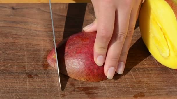 nainen käsi siivu kypsä ekologinen mango hedelmä veitsi puinen lauta
 - Materiaali, video