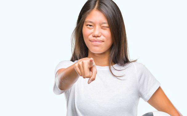 Mladá asijská žena držící fotbal fotbalový míč, samostatný pozadí ukazuje prstem do kamery a vám, ručně podepsat, pozitivní a sebevědomý gesto zepředu - Fotografie, Obrázek