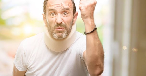 Hombre mayor lesionado usando un corsé en el cuello irritado y enojado expresando emociones negativas, molesto con alguien
 - Foto, Imagen