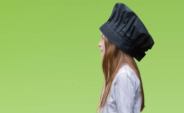 Молода красива дівчина у формі капелюха шеф-кухаря над ізольованим тлом, дивлячись в бік, розслабляє профільну позу з природним обличчям з впевненою посмішкою
. - Фото, зображення