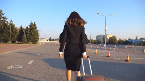 Üzleti nő a bőröndjét haladva airport taxi parkoló. Hölgy séta város utca mentén a csomagokkal. Női lábak magas sarkú cipő, megerősítése a járdán. Hátsó vissza Nézd lassú mozgás - Felvétel, videó