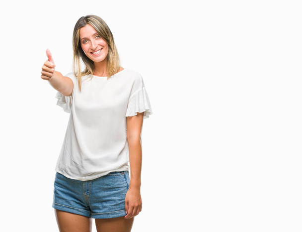 Young beautiful woman over isolated background doing happy thumbs up gesture with hand. Approving expression looking at the camera with showing success. - Photo, Image