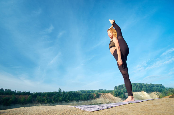 Atractiva mujer pelirroja deportiva rizada estirándose al aire libre. Concepto amor yoga. Concepto amor mañana
 - Foto, Imagen