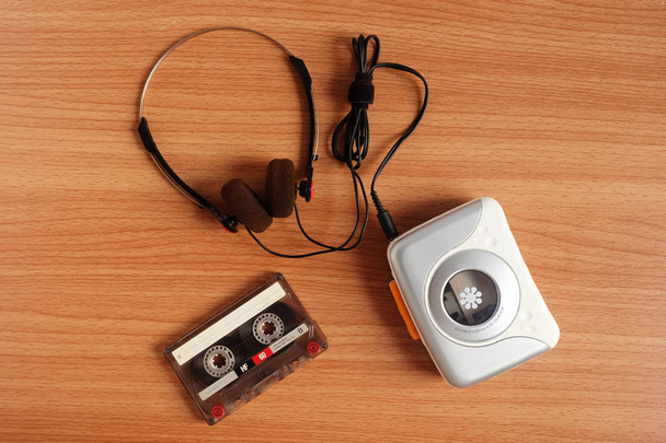 Oude draagbare cassette tape-speler en de koptelefoon op houten vloer - Foto, afbeelding