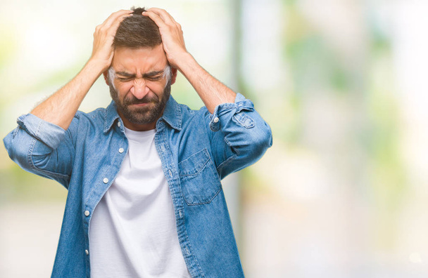 Volwassen Spaanse man over geïsoleerde achtergrond lijden hoofdpijn wanhopig en benadrukt omdat pijn en migraine. Handen op het hoofd. - Foto, afbeelding