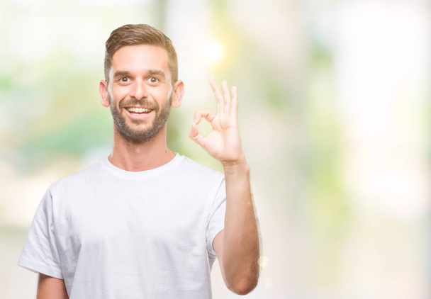 Mladý pohledný muž nad usmívá izolovaná pozadí pozitivní jednání ok znamení rukou a prstů. Úspěšné výraz. - Fotografie, Obrázek