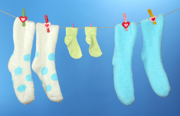 Colorful socks hanging on clothesline, on color background - Foto, Imagen