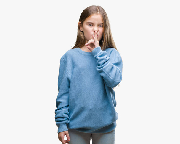 Молода красива дівчина в зимовому светрі над ізольованим тлом просить мовчати з пальцем на губах. Тиша і таємна концепція
. - Фото, зображення