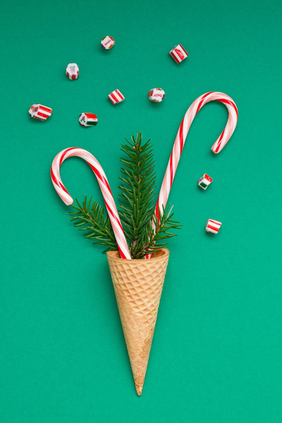正月クリスマス ホリデー パーティーお祝いワッフル コーン キャンディの杖 fir ツリー ブランチ コピー スペース緑の色用紙の背景。テンプレート グリーティング カード 2019 - 写真・画像