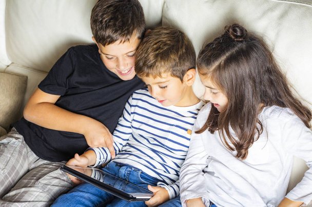 Three kids using a tablet at home - Fotoğraf, Görsel