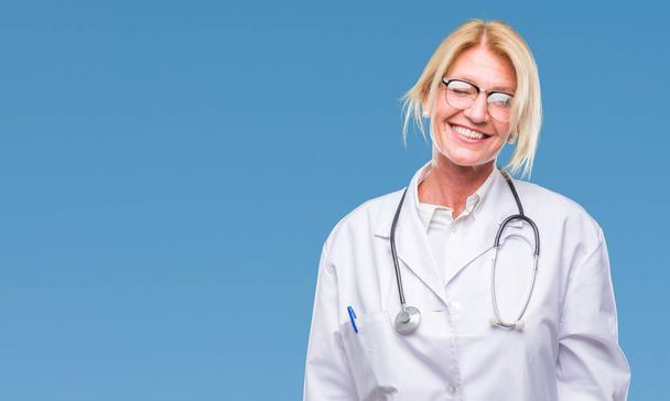 Blonde Ärztin mittleren Alters über isoliertem Hintergrund, zwinkernd in die Kamera blickend mit sexy Gesichtsausdruck, fröhlichem und glücklichem Gesicht. - Foto, Bild