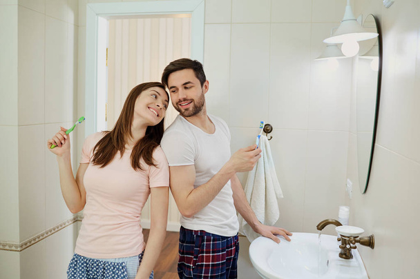 Couple in the morning personal hygiene in the bathroom - Фото, зображення