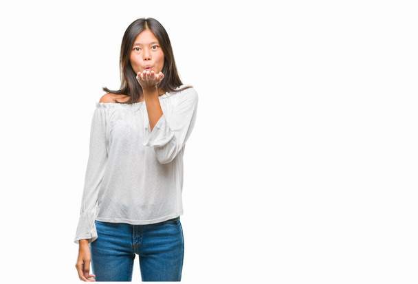 Jonge Aziatische vrouw over geïsoleerde achtergrond kijken naar de camera een kus met hand blazen op lucht wordt mooi en sexy. Hou van expressie. - Foto, afbeelding