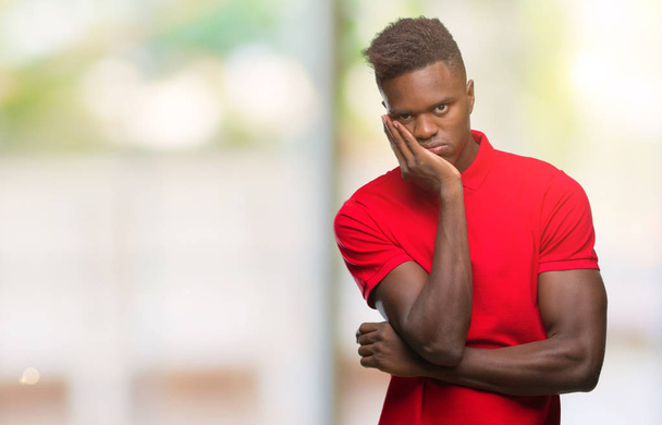 Jonge Afro-Amerikaanse man over geïsoleerde achtergrond denken op zoek moe en verveeld met depressie problemen met gekruiste armen. - Foto, afbeelding