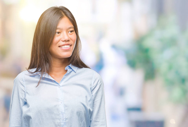 Молода азіатська бізнес-леді над ізольованим тлом дивиться в сторону з посмішкою на обличчі, природним виразом. Сміється впевнено
. - Фото, зображення