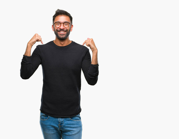 Hombre hispano adulto con gafas sobre un fondo aislado que mira confiado con sonrisa en la cara, señalándose con los dedos orgullosos y felices
. - Foto, imagen