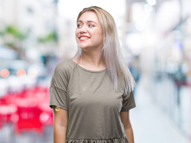 Jeune femme blonde sur fond isolé regardant de côté avec le sourire sur le visage, expression naturelle. Rire confiant
. - Photo, image