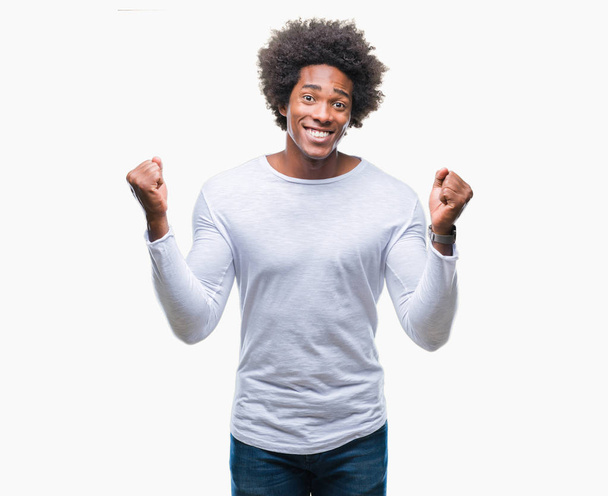 Homem afro-americano sobre fundo isolado comemorando surpreso e surpreso pelo sucesso com braços levantados e olhos abertos. Conceito de vencedor
. - Foto, Imagem