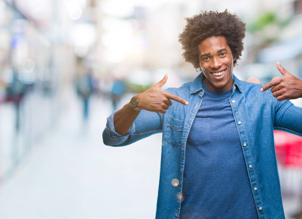 Afro american mężczyzna na białym tle patrząc pewny siebie z uśmiechem na twarzy, wskazując siebie palcami, dumny i szczęśliwy. - Zdjęcie, obraz