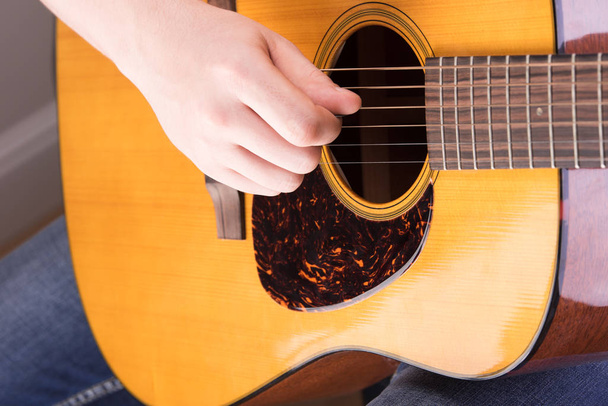 Playing on acoustic guitar close-up. Male hand to pluck the strings - 写真・画像