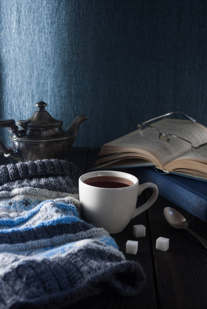 Cup of tea, book and knit cap on a wooden table - Foto, afbeelding
