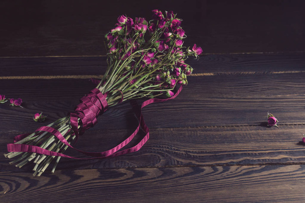 Bouquet of dry flowers with a ribbon on the dark wooden surface - Foto, Bild