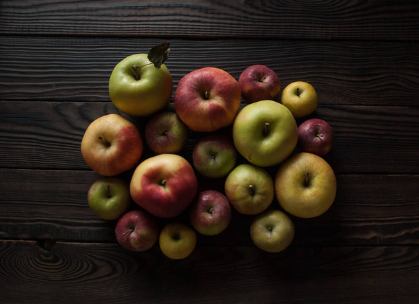 Group of colored apples of different sizes on a wooden surface - Fotografie, Obrázek