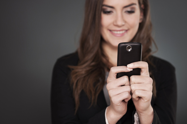 Cheerful businesswoman texting on mobile phone - Photo, Image