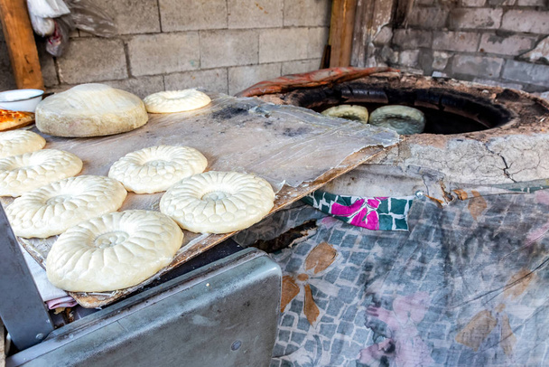 Традиційний узбекський круглий плоский хліб готується покласти в танір
 - Фото, зображення