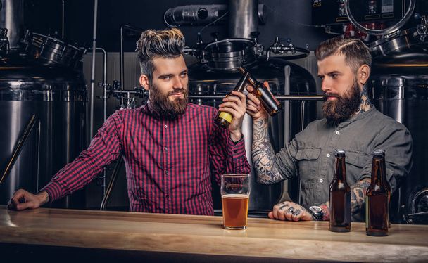 流行に敏感な友人インディーズ醸造所でビールを一緒に飲む 2 つのスタイリッシュなひげを生やした. - 写真・画像
