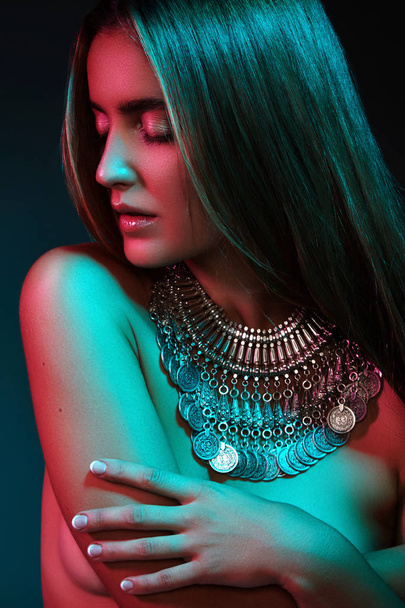 Beautiful woman in a necklace. Model in jewelry from silver. Beautiful indian jewellery. Bright lights photo effect - Fotó, kép
