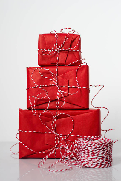 Christmas gift boxes wrapped in red paper and bow of dtriped rope on white background - Φωτογραφία, εικόνα