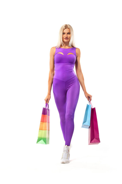 Black friday sale concept for fitness shops. Shopping woman athlete holding color bag isolated on yellow background in holiday - Φωτογραφία, εικόνα