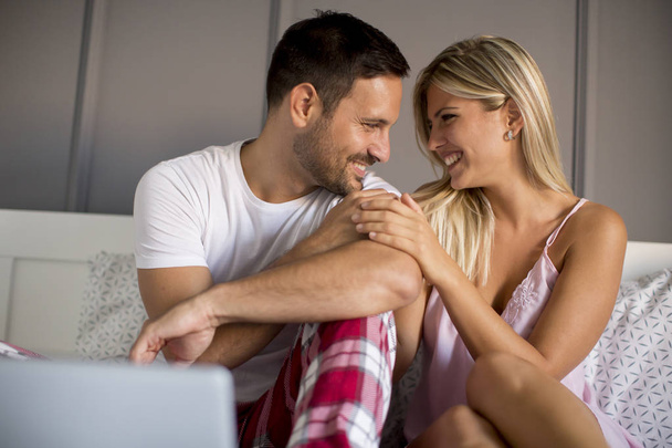 Couple aimant avec ordinateur portable dans le lit à la maison
 - Photo, image