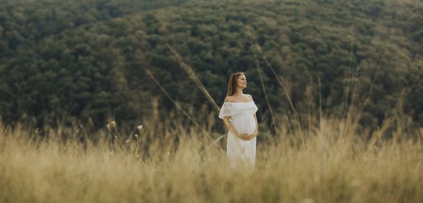 Молодая беременная женщина отдыхает на природе в летний день
 - Фото, изображение