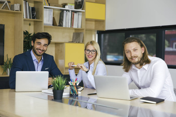 Jóvenes empresarios que usan computadoras y sonríen mientras trabajan en la oficina
 - Foto, imagen