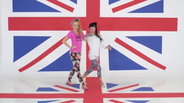 Zkouška dvou roztomilých vtipné dívky tančí na pozadí textury vlajka Velké Británie. - Záběry, video