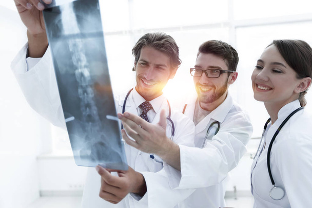 Three confident doctors examine an x-ray - Foto, Bild