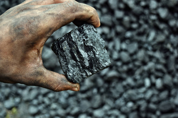Άνθρακα στο χέρι του εργαζόμενου ανθρακωρύχος. Εικόνα μπορεί να χρησιμοποιηθεί για την ιδέα για την εξόρυξη άνθρακα, ενέργεια πηγή ή περιβάλλον προστασία. - Φωτογραφία, εικόνα