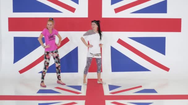 Zkouška dvou legrační usmívající se žen, které tančí na pozadí textury vlajka Velké Británie. - Záběry, video