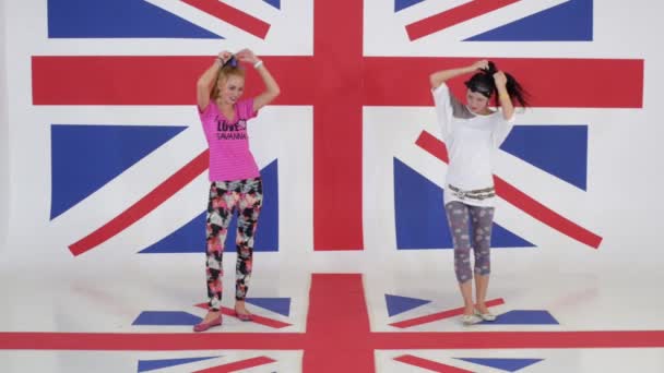 Cvičení ze dvou docela vtipné dívky tančí ve studiu s tapetami vlajky Velké Británie - Záběry, video