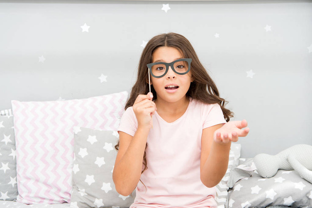 Slumber party photo booth props. Kid girl wondering posing with vintage eyeglasses party attribute. Prepare photo booth props hand made or buy for party. Printable photo booth props pajama party - Foto, Imagen