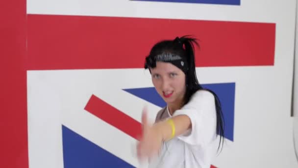 gut aussehende dunkelhaarige Mädchen tanzt energisch auf dem Hintergrund der britischen Flagge - Filmmaterial, Video