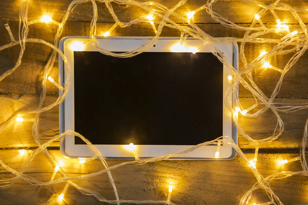 High angle view of messy Christmas lights with a digital tablet on the wooden table - Fotoğraf, Görsel
